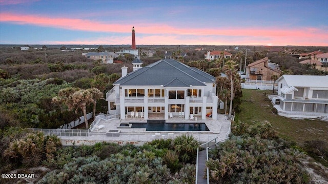 rear view of property with an outdoor pool, a patio, a balcony, and fence