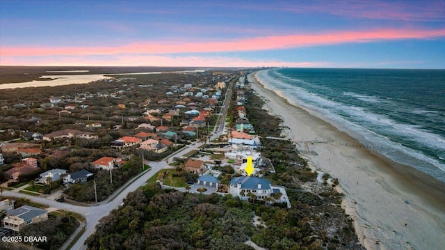 aerial view at dusk featuring a beach view and a water view