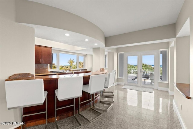 kitchen featuring a breakfast bar area, granite finish floor, recessed lighting, and baseboards