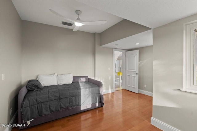 bedroom featuring a ceiling fan, visible vents, wood finished floors, and baseboards