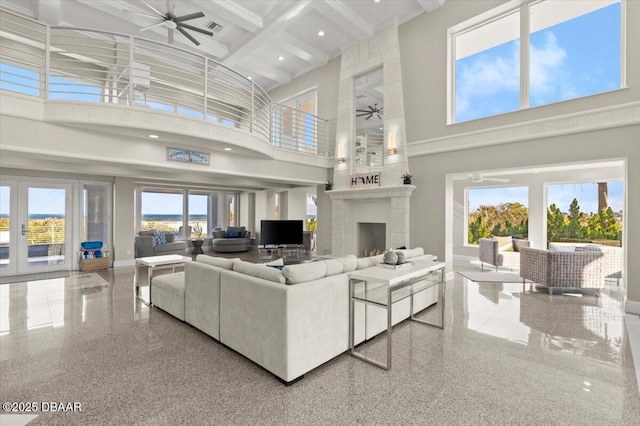 living area featuring a ceiling fan, coffered ceiling, a high ceiling, a fireplace, and baseboards