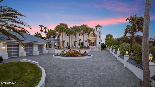 view of front facade featuring decorative driveway, fence, and stucco siding