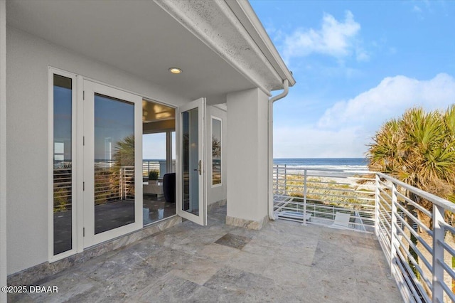 balcony with a water view and a view of the beach