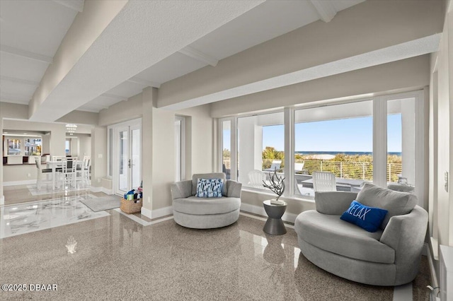 living area with granite finish floor, beamed ceiling, and baseboards