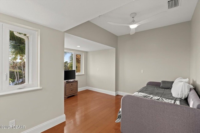 living area featuring a ceiling fan, visible vents, wood finished floors, and baseboards