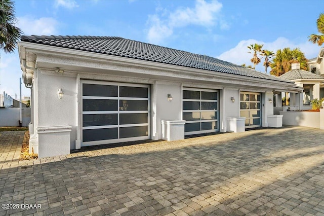 exterior space with a tile roof, a garage, and stucco siding