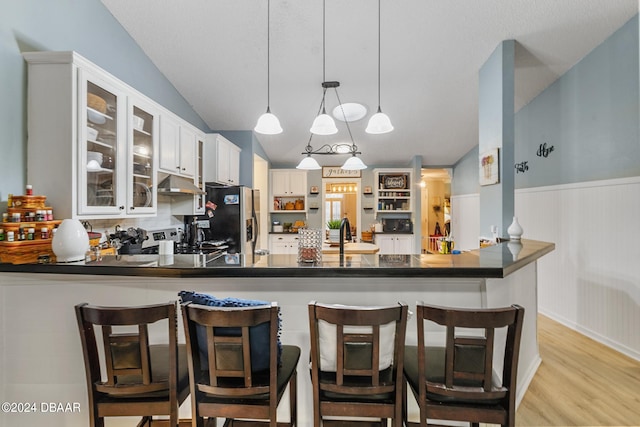 10 Pine Brook Dr, Palm Coast, FL 32164 - kitchen with white cabinetry, kitchen peninsula, hanging light fixtures, and a breakfast bar area