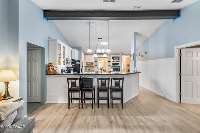 10 Pine Brook Dr, Palm Coast, FL 32164 - kitchen featuring light hardwood / wood-style floors, black refrigerator, a kitchen breakfast bar, white cabinetry, and decorative light fixtures