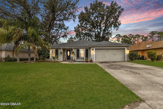 single story home featuring a garage and a lawn