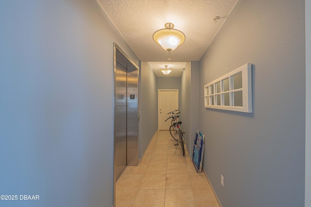3756 S Atlantic Ave Unit 101, Daytona Beach, FL 32118 - hallway featuring light tile patterned floors, a textured ceiling, elevator, and baseboards
