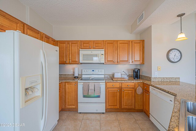 3756 S Atlantic Ave Unit 101, Daytona Beach, FL 32118 - kitchen featuring light tile patterned floors, brown cabinetry, visible vents, white appliances, and a textured ceiling