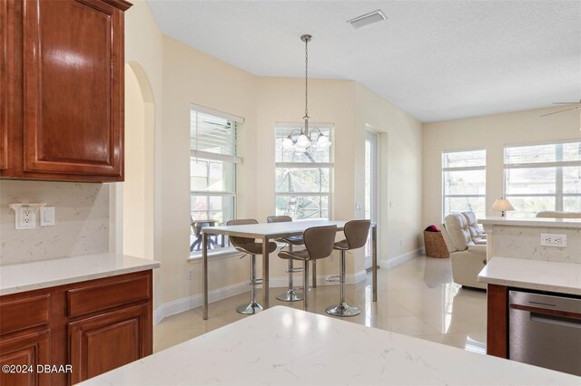 kitchen featuring dishwasher, decorative backsplash, a textured ceiling, light tile patterned floors, and pendant lighting