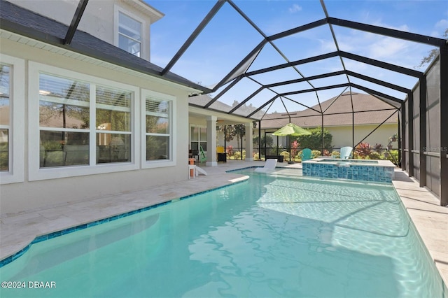 view of pool featuring a patio, glass enclosure, and an in ground hot tub