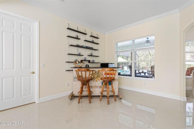 tiled dining room with a textured ceiling and crown molding