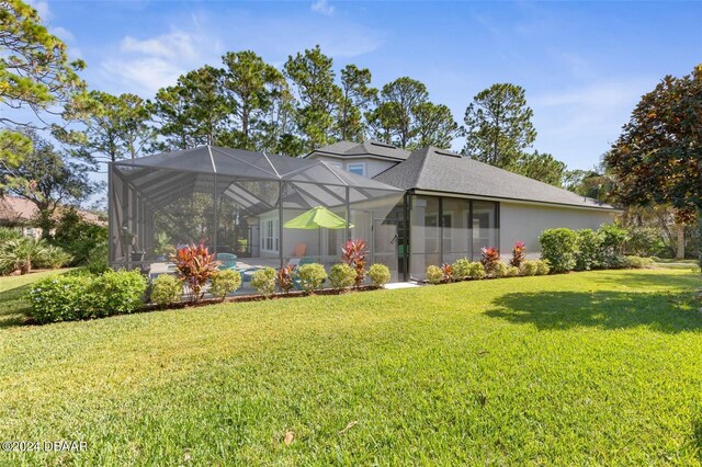 back of house featuring a lanai and a yard