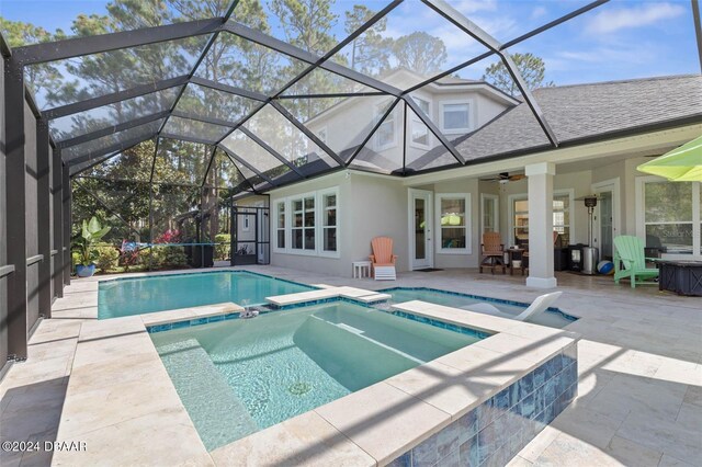 view of pool with glass enclosure, a patio area, ceiling fan, and an in ground hot tub