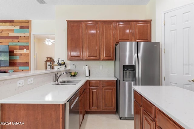 kitchen featuring kitchen peninsula, sink, ceiling fan, light stone countertops, and appliances with stainless steel finishes