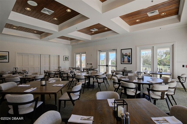 carpeted dining room with wooden ceiling, a towering ceiling, crown molding, coffered ceiling, and french doors