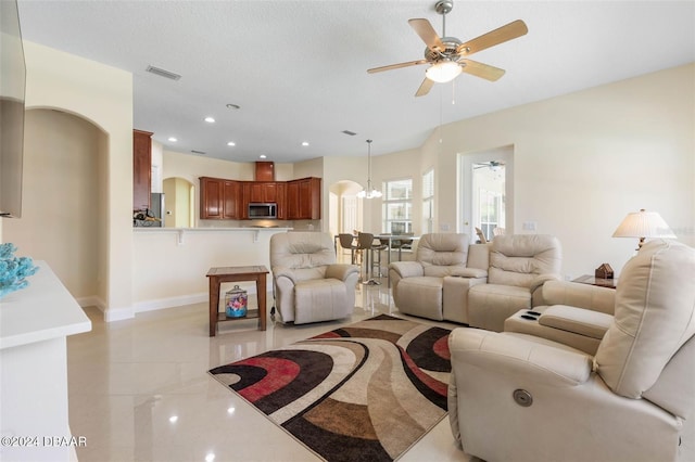 living room featuring ceiling fan with notable chandelier and a textured ceiling