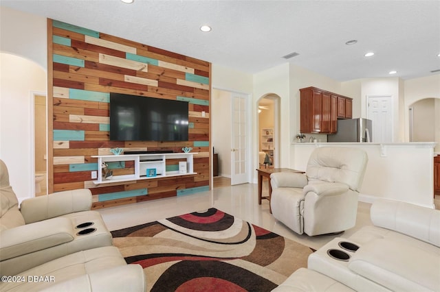 living room with a textured ceiling, wooden walls, and light hardwood / wood-style flooring