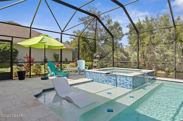 view of swimming pool featuring glass enclosure, a patio, pool water feature, and an in ground hot tub