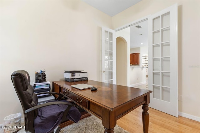 home office with french doors and light hardwood / wood-style flooring