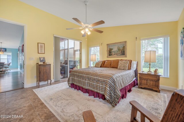 tiled bedroom with multiple windows, vaulted ceiling, and ceiling fan