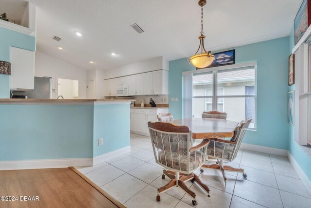 dining space with vaulted ceiling and light tile patterned flooring