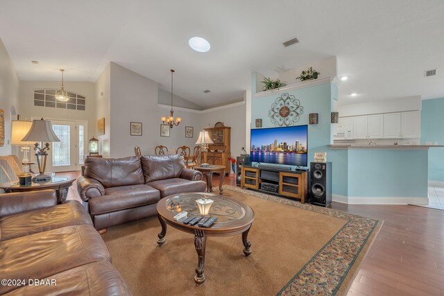 living room with high vaulted ceiling, an inviting chandelier, and hardwood / wood-style floors