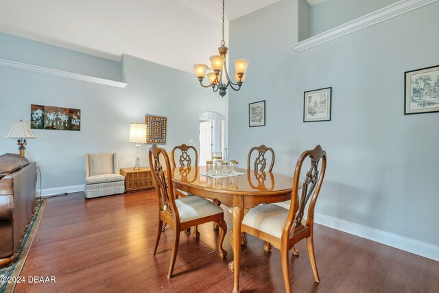 dining area with dark wood-type flooring, a notable chandelier, and a towering ceiling