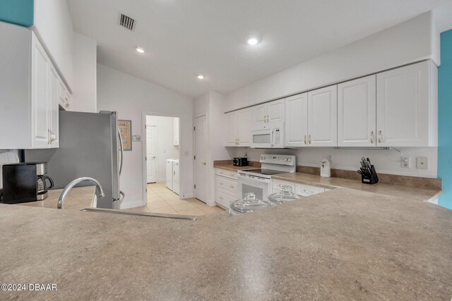 kitchen featuring white appliances, separate washer and dryer, white cabinetry, and vaulted ceiling