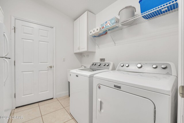 laundry room featuring cabinets, light tile patterned floors, and washer and clothes dryer