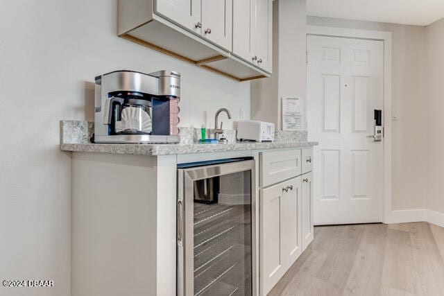 350 N Atlantic Ave Unit 2124, Daytona Beach, FL 32118 - kitchen featuring wine cooler, light stone countertops, light hardwood / wood-style floors, and white cabinets