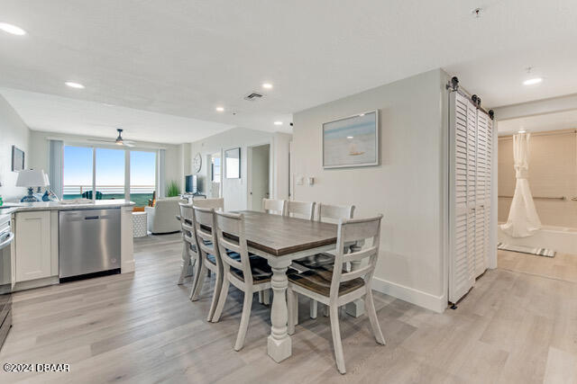 350 N Atlantic Ave Unit 2124, Daytona Beach, FL 32118 - dining space with light hardwood / wood-style flooring, a barn door, and ceiling fan