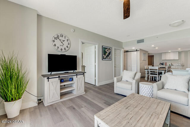 350 N Atlantic Ave Unit 2124, Daytona Beach, FL 32118 - living room featuring a barn door, ceiling fan, and light wood-type flooring