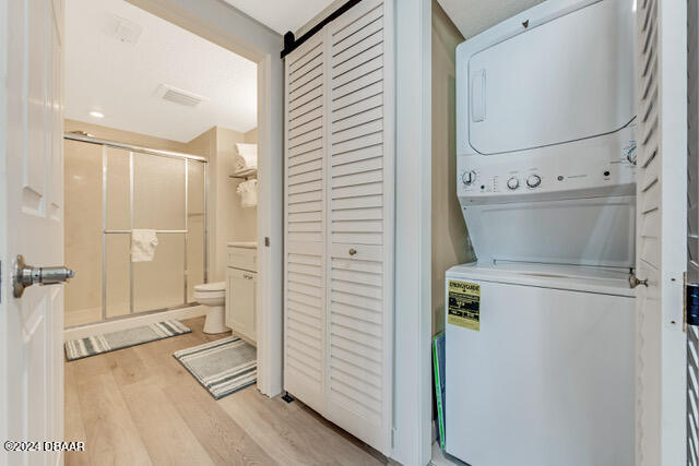 350 N Atlantic Ave Unit 2124, Daytona Beach, FL 32118 - laundry room featuring stacked washer and dryer and light wood-type flooring