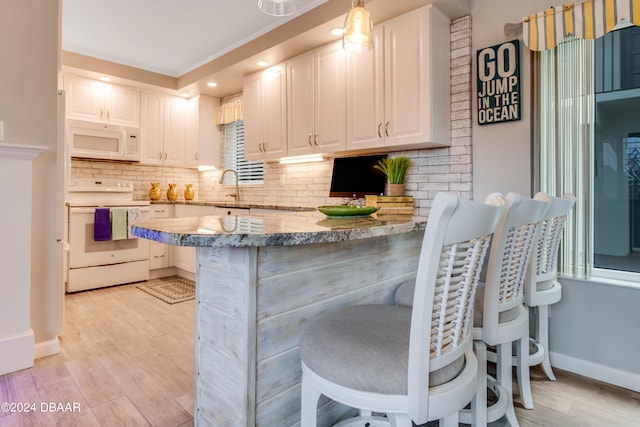 kitchen with kitchen peninsula, white appliances, decorative light fixtures, and white cabinets