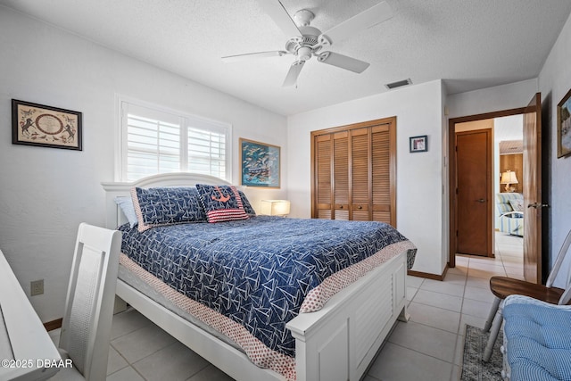 bedroom with ceiling fan, a closet, a textured ceiling, and light tile patterned flooring