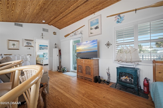 living room featuring vaulted ceiling, hardwood / wood-style floors, a wood stove, and wooden ceiling