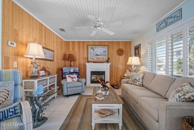 tiled living room with ceiling fan, wooden ceiling, and wooden walls