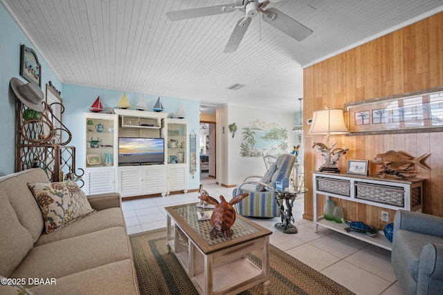 living room featuring light tile patterned floors, wooden ceiling, ceiling fan, and wood walls