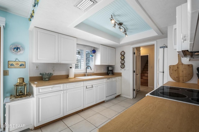 kitchen featuring light tile patterned floors, sink, white appliances, white cabinets, and a raised ceiling