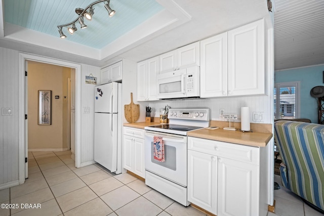 kitchen featuring light tile patterned flooring, white cabinets, white appliances, and a tray ceiling