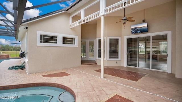 view of patio / terrace with ceiling fan, a pool, and glass enclosure