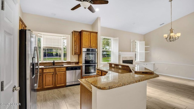 kitchen featuring a center island, sink, hanging light fixtures, stainless steel appliances, and light stone counters