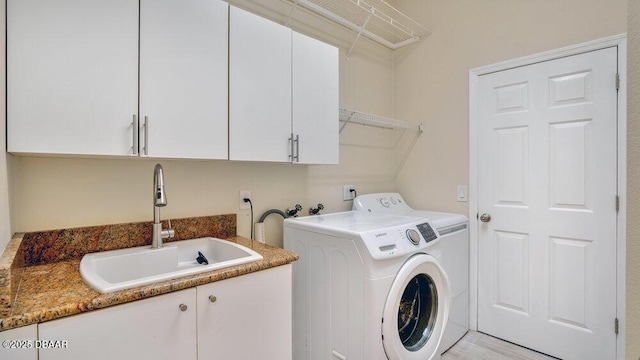 clothes washing area featuring washing machine and dryer, sink, and cabinets