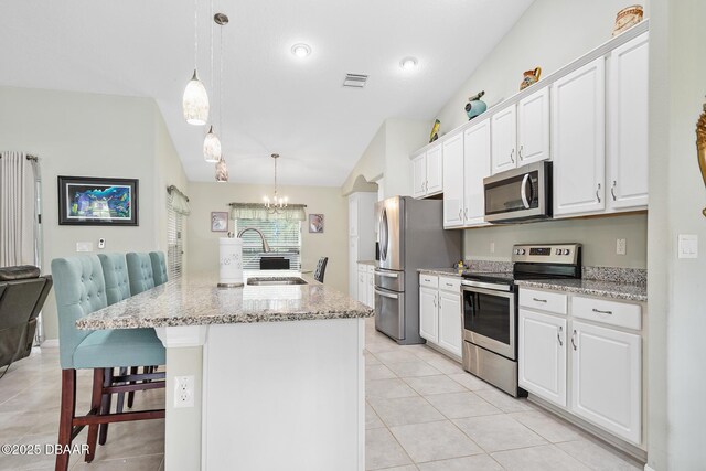 118 Bird Of Paradise Dr, Palm Coast, FL 32137 - kitchen with appliances with stainless steel finishes, vaulted ceiling, white cabinetry, light tile patterned floors, and a kitchen breakfast bar