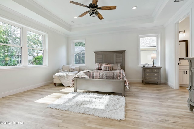 bedroom with ornamental molding, light wood-type flooring, a tray ceiling, and ceiling fan