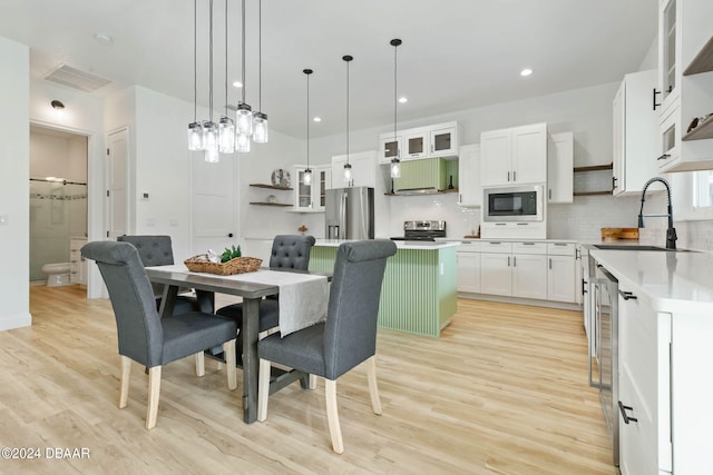 kitchen featuring stainless steel appliances, sink, hanging light fixtures, a center island, and white cabinets