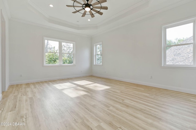 empty room featuring ornamental molding, light hardwood / wood-style flooring, ceiling fan, and a raised ceiling